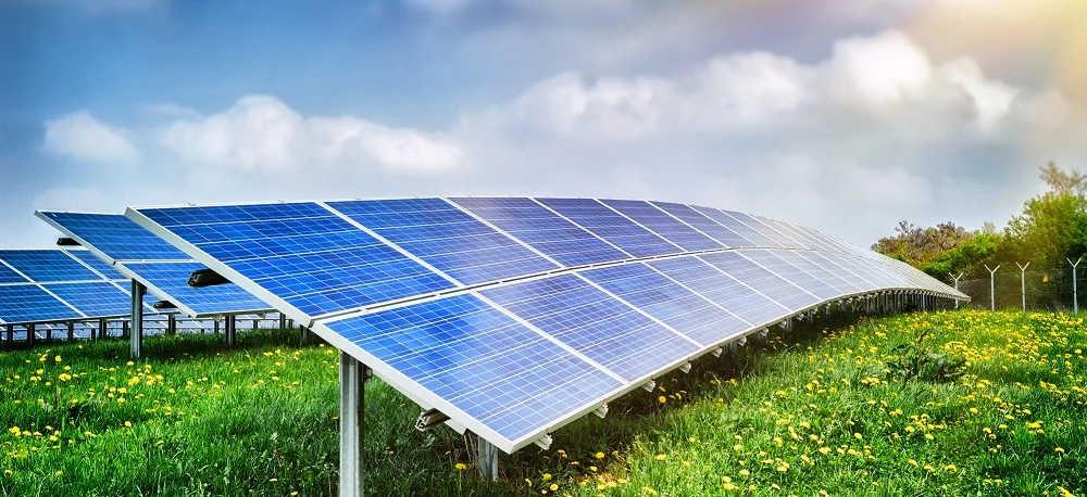 Pole paneli słonecznych generujących czystą energię w ustawieniu rolniczym. Energia słoneczna i wiatrowa używana do produkcji plonów na plantacji.