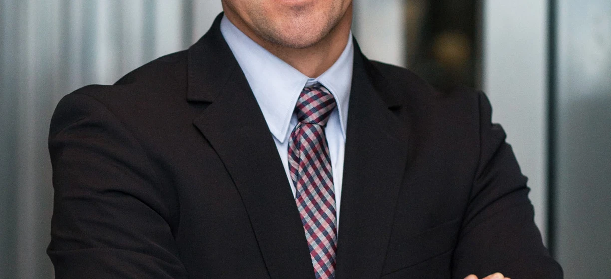 Mężczyzna w eleganckim ubraniu uśmiecha się, nosząc okulary z kołnierzykiem i z podwiniętymi rękawami. Zadbana higiena wzroku jest ważna dla eleganckiego wyglądu.