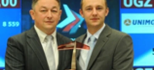 Uśmiechnięty pracownik biurowy w formalnym ubraniu z logo na koszuli, reprezentujący profesjonalizm i satysfakcję z pracy. 

Słowa kluczowe: Formalne ubranie, Garnitur, Marynarka, Płaszcz, Pracownik biurowy, Krawat, Koszula do garnituru, Uśmiech, Praca, Logo.