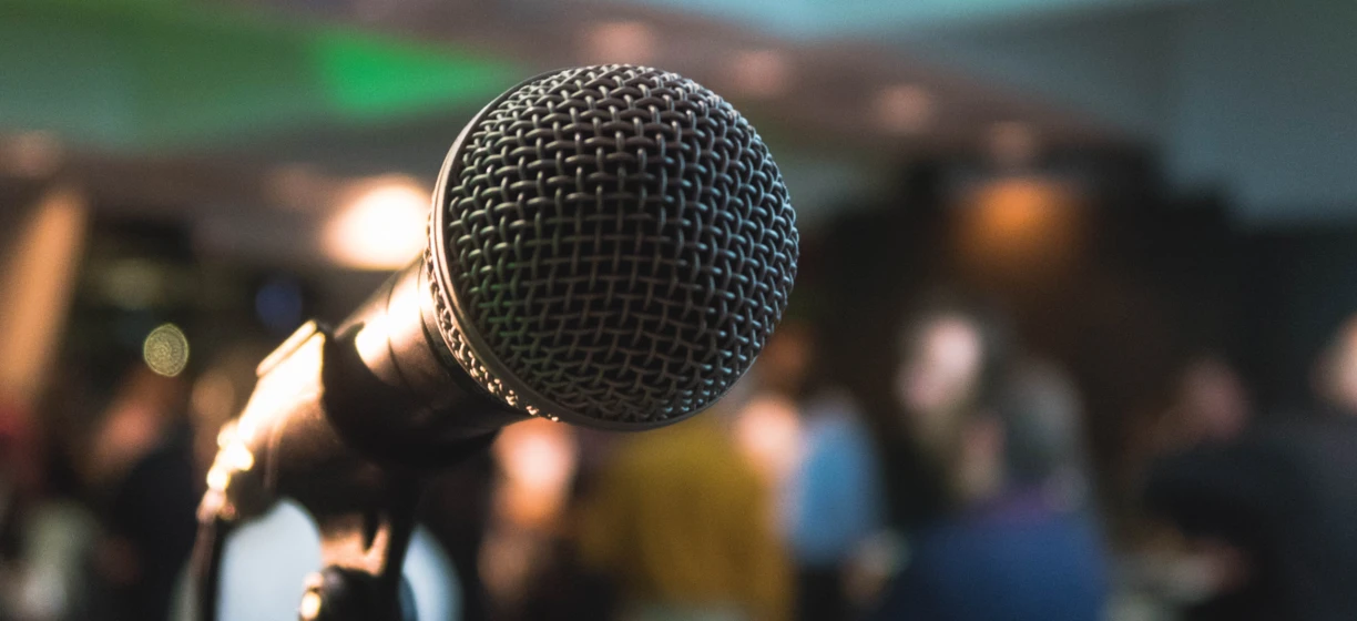 Stojak na mikrofon przed urządzeniem elektronicznym i sprzętem audio na wydarzeniu publicznym. Sztuka sceniczna i rozrywka z systemem nagłaśniającym dla występu na żywo.