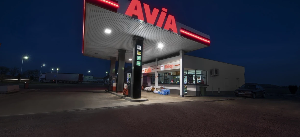 Tablica stacji paliw w języku polskim informująca o benzynie AVIA ON Gold 98. Na miejscu dostępny sklep.