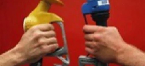 Handlowiec w roboczym ubraniu używa dyszy dystrybutora paliwa, aby napełnić maszynę paliwem przez rurę i wąż.