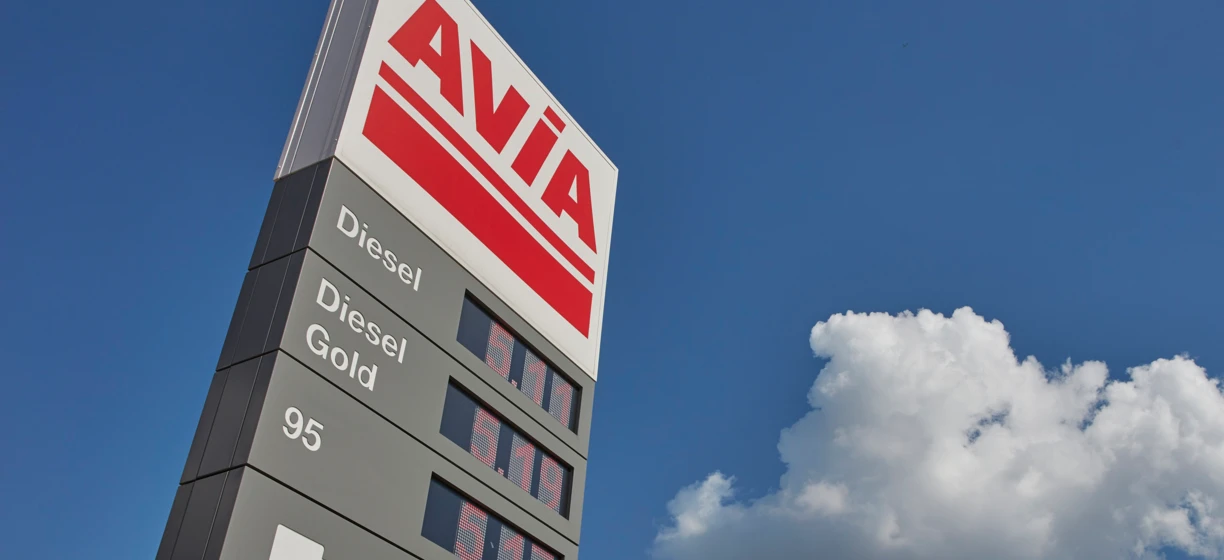 Reklama paliwa diesel AVIA z lusterkiem i zderzakiem samochodowym. Promocja paliwa Gold 95 T w języku polskim.