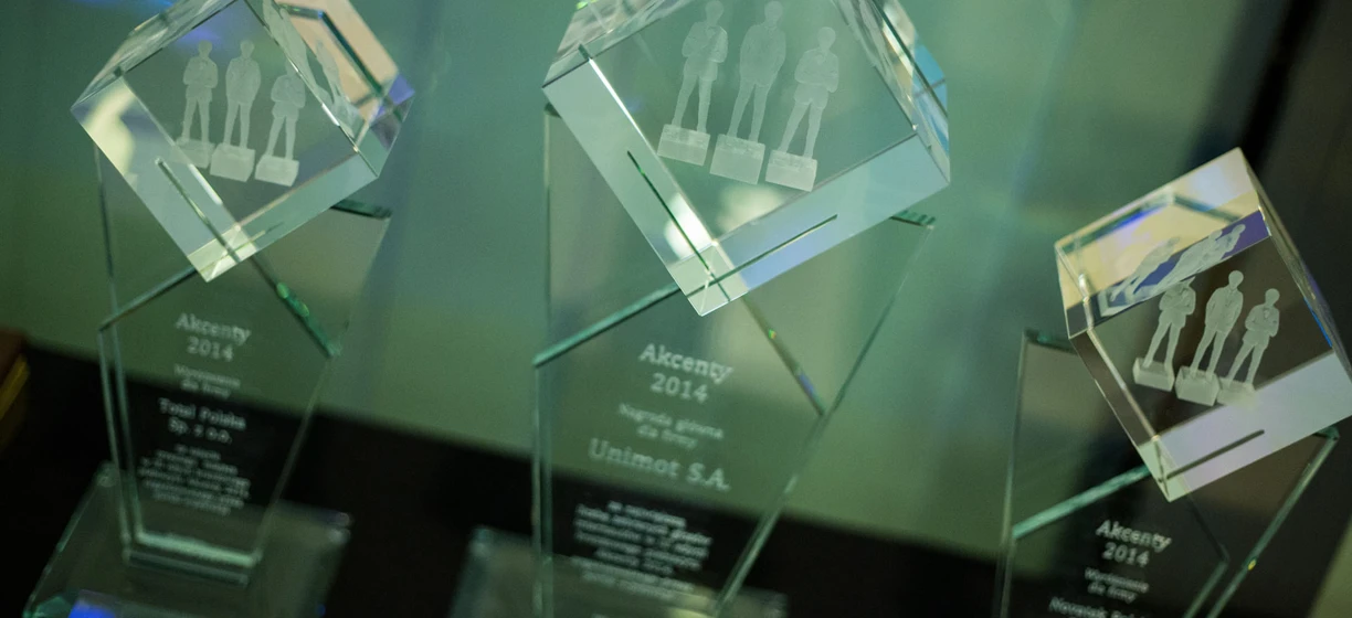 Srebrny puchar nagrody wyświetlany w przezroczystej obudowie prezentującej jego projekt wykonany z naturalnych materiałów. Zwycięzca nagrody Akcenty 2014 od firmy Unimot S.A.