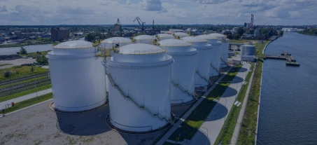 Wysoka zbiornik na składowanie zboża odbijający się w wodzie na zewnątrz fabryki w otoczeniu przemysłowym. Jasny i pogodny dzień. Atmosfera przemysłowa.