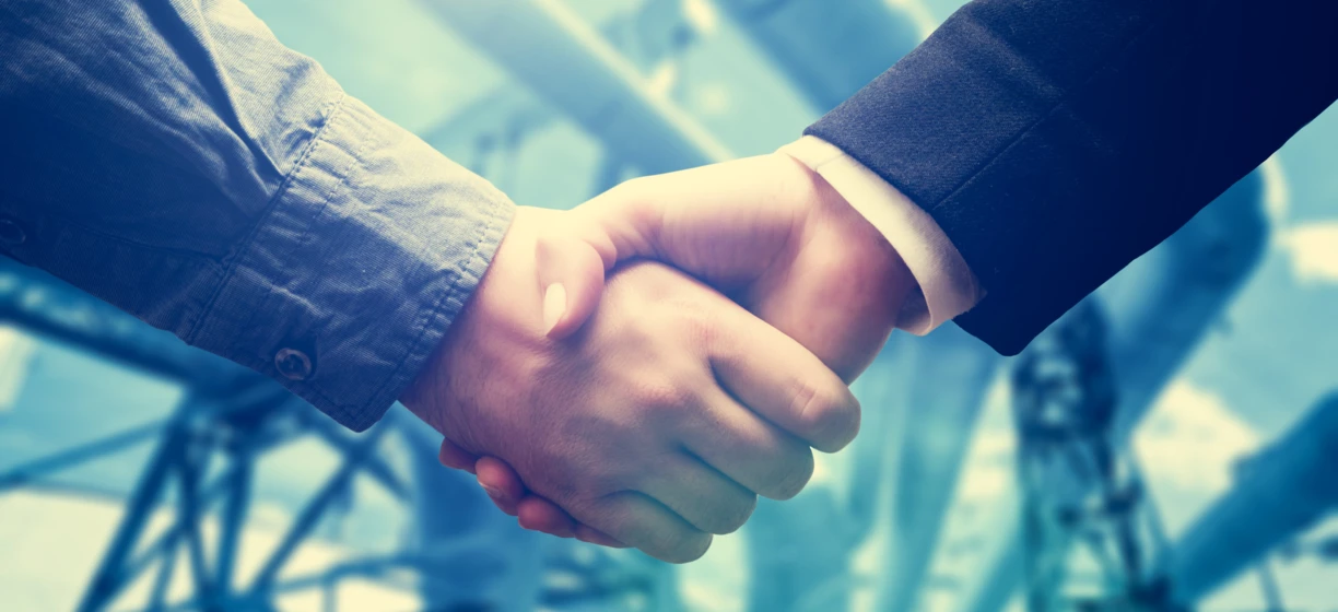 Dwie osoby podające sobie ręce w geście przywitania i współpracy, pokazując działający zespół i efektywne zarządzanie.