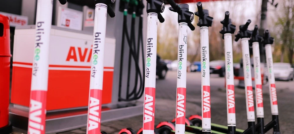 Alternatywny tekst: Kolorowa reklama przedstawiająca różne części rowerowe, takie jak ramy, koła, szprychy, kierownice, opony i widelce, z tekstem "blinkee.city AVIA" powtarzanym wielokrotnie. Ostrożnie zbliż się do tego unikalnego wyposażenia rowerowego!