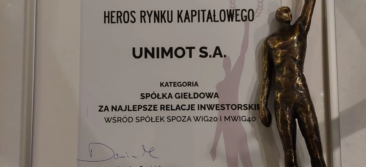 Nagroda dla Najlepszych Relacji Inwestorskich wśród firm spoza WIG20 i MWIG40. Przyznana UNIMOT S.A. przez Stowarzyszenie Inwestorów Indywidualnych. Jarosław Dominiak, Prezes Stowarzyszenia, przyjmuje trofeum na podium z mosiężną banderą.