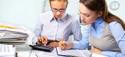 Zagracany biurko z artykułami biurowymi i papierem, symbolizujący zabiegane stanowisko pracy lub środowisko nauki studenta. Przestrzeń do pracy białego kołnierza lub studenta.