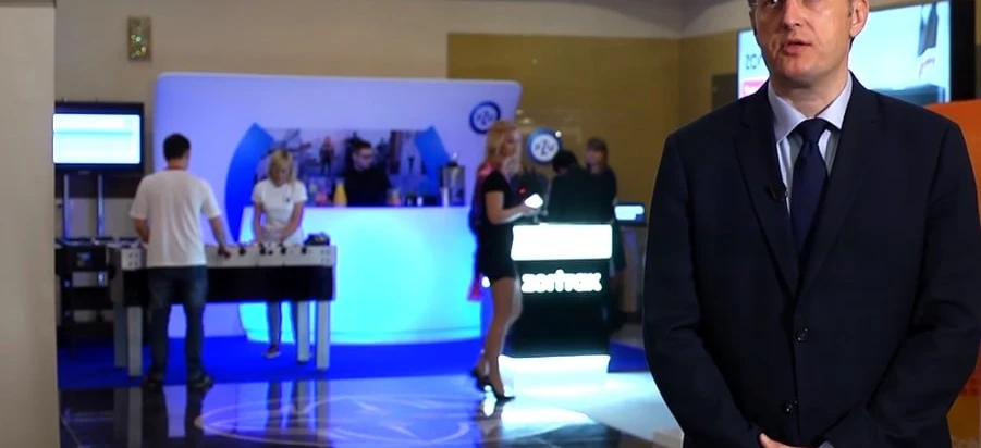 Pracownik biurowy w białym garniturze korzystający z urządzenia wyświetlającego do transmisji multimedialnych, prezentujący technologię inwestorom w telewizji.