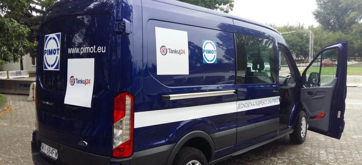 Tekst alternatywny: Widok boczny kompaktowego vana z logo PIMOT i Tankuj24. Elementy obejmują lusterko boczne, zderzak, drzwi samochodu i kołpak. Pojazd użytkowy Ford Motor Company.