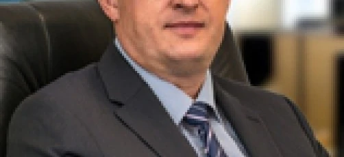 Biznesmen w eleganckim ubraniu siedzący w okularach i koszuli, symbolizujący profesjonalizm i troskę o wzrok.