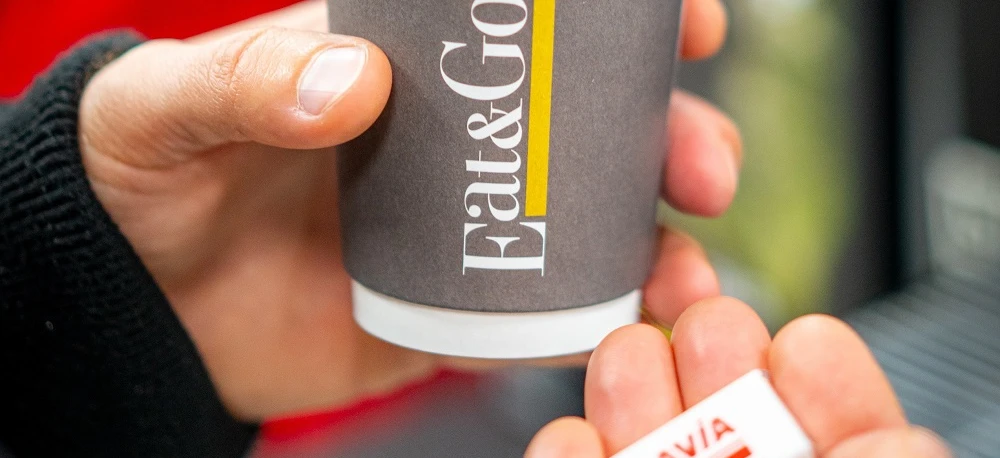 "Owijka na kubek do kawy z logo AVIA i napisem 'Fat&Go' obok kubka z jedzeniem."