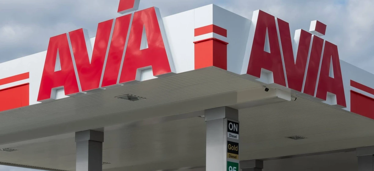 Stacja paliw z różnorodnymi opcjami oleju napędowego dla ciężarówek i SUV-ów, w tym AVA i AVIA. Pojazdy zaparkowane przy pompach z odbijającymi lusterkami.