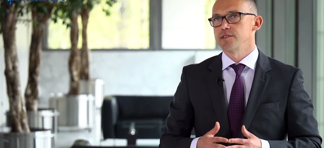 Pracownik umysłowy stojący pewnie w eleganckim ubraniu i okularach, symbolizujący profesjonalizm i dbałość o wzrok. #InvestorzyTy #CeleModowe