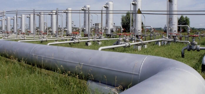 Rozprowadzanie w przemyśle rur stalowych do obudowy w celach transportu rurociągów i inżynieryjnych. Widoczne są również metalowe cylindry i zbiorniki magazynowe.