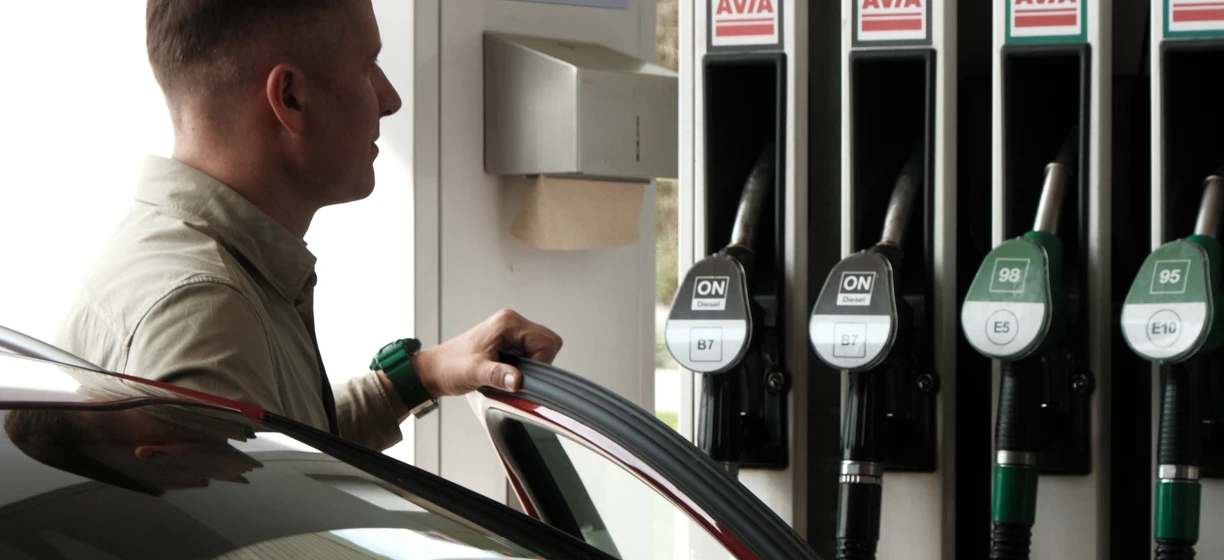 Dystrybutor paliwa na stacji benzynowej z luksusowym samochodem zaparkowanym przy dystrybutorze. Słowa kluczowe: Paliwo, Benzyna, Pojazd elektryczny, Maszyna.