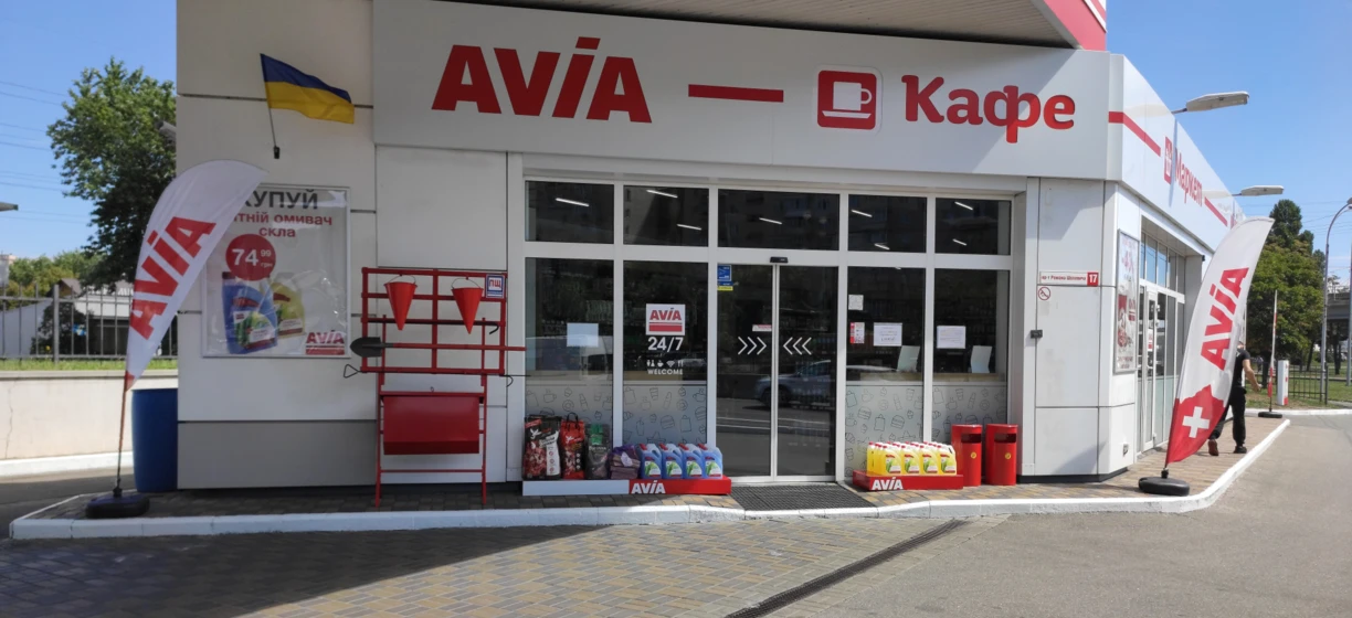 Reklama dla lekkich samochodów dostawczych AVIA o numerze VIN 7499. Zaparkowane na wyznaczonym miejscu z kołpakami oraz włączonymi światłami stopu i hamowania. Wyraźnie wyświetlone logo oraz informacje kontaktowe.