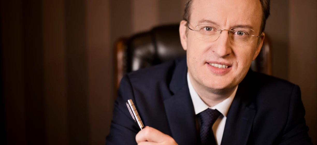 Mężczyzna w eleganckim ubraniu w okularach na czole, palec na brodzie, prezentujący opiekę nad wzrokiem.