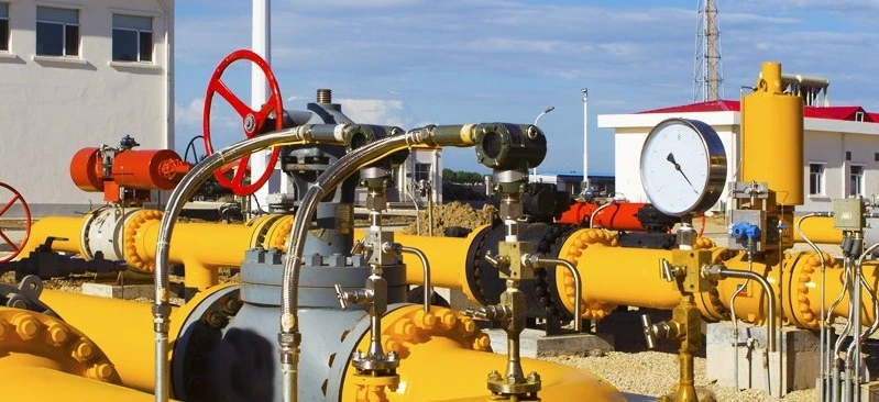 Stalowa rura łączy maszynę z stacją pompowania w fabryce przemysłowej. Inżynieria spotyka się z przemysłem w tym złożonym systemie cylindrów i zaworów.