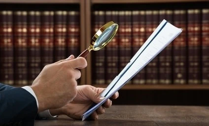 Pracownik umysłowy korzystający z lupki do badania dokumentu. Artykuły biurowe i sprzęt w tle. SEO: Osoba prowadząca biznes korzystająca z lupki w ustawieniu biurowym.