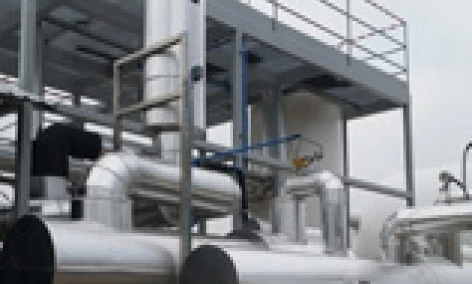 Zbliżenie rur metalowych produkowanych przez maszynę w przemyśle, wykonanych z materiałów kompozytowych. Widoczne są rury obudowy z żelaza i stali, prezentujące zaangażowane procesy inżynieryjne.