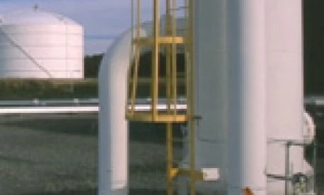 Rura metalowa połączona z zbiornikiem w ustawieniu przemysłowym. Inżynieria oraz maszyny pracujące z materiałami kompozytowymi.