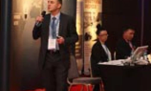 Grupa elegancko ubranych pracowników biurowych w garniturach i spodniach na formalnym wydarzeniu, z technologią w tle. Reklama odzieży męskiej na galę.