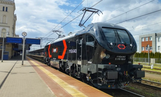 Nowoczesna lokomotywa zasilana elektrycznie podróżuje po torach pod napiętymi liniami zasilającymi w Polsce. Transport publiczny jest niezbędny dla efektywnego przemieszczania ludzi i towarów.