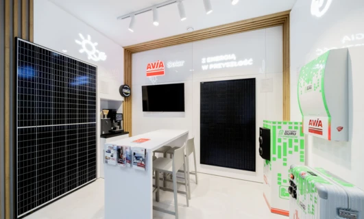 Projekt wnętrza obejmujący eleganckie urządzenie elektroniczne z technologią podświetlenia LED w technologii LCD. Pod telewizorem LCD stoi fotel wyświetlający różne loga marek.