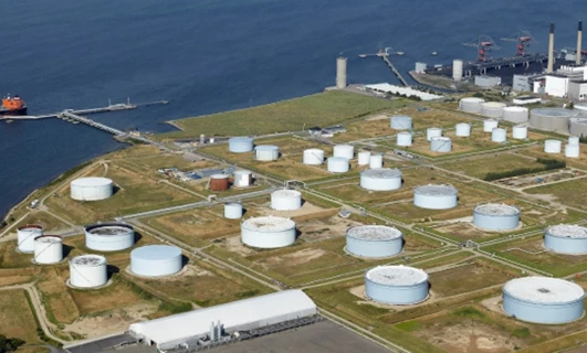 Widok z powietrza na kompleks przemysłowy z zbiornikami magazynowymi, silosami i elektrownią. Fabryka tętniąca życiem.