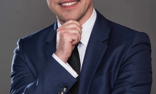 Osoba nosząca okulary i formalną białą koszulę z kołnierzykiem, z widoczną brodą i brwiami. Dbanie o wzrok jest ważne dla dobrego wzroku.