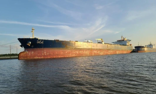 Duży tankowiec płynie po wodzie pod zachmurzonym niebem. Architektura okrętu jest imponująca, gdyż przewozi ładunek płynny.