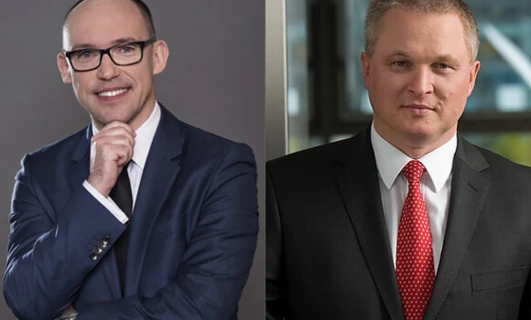 Mężczyzna w okularach i formalnym ubiorze poprawiający kołnierzyk, prezentujący stylowy wygląd. Okulistyka i moda łączą się harmonijnie w tej nowoczesnej fotografii.