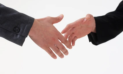 Dwóch biznesmenów witających się uściskiem dłoni, symbolizujących współpracę i partnerskie relacje zawodowe. Pracownicy biurowi wyrażający szacunek i współpracę za pomocą prostego gestu.