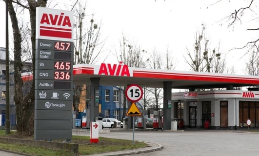 Pojazd zaparkowany na stacji benzynowej z różnymi opcjami paliwa, w tym olejem napędowym, Gold 95 i CNG. Wyraźnie widoczna marka AViA.