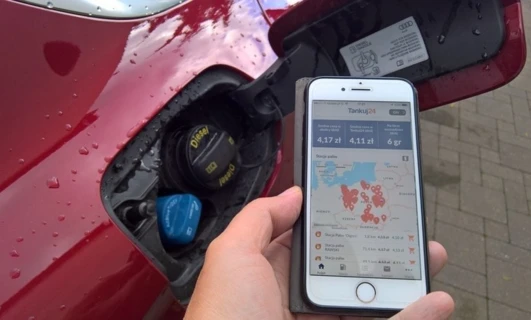 Samochód sportowy z elegancką sylwetką, wyposażony w drzwi samochodowe, przednią szybę oraz światło tylne i hamulcowe. Telefon komórkowy podłączony do pojazdu elektrycznego w celach FIDE i ITO.