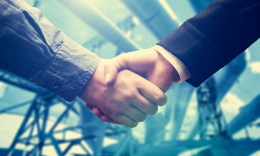 Dwie osoby podające sobie ręce w geście przywitania i współpracy, pokazując działający zespół i efektywne zarządzanie.