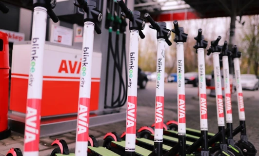 Alternatywny tekst: Kolorowa reklama przedstawiająca różne części rowerowe, takie jak ramy, koła, szprychy, kierownice, opony i widelce, z tekstem "blinkee.city AVIA" powtarzanym wielokrotnie. Ostrożnie zbliż się do tego unikalnego wyposażenia rowerowego!