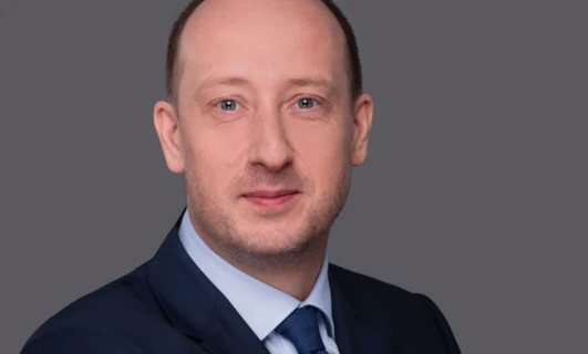 Zblizenie twarzy osoby pokazującej podbródek, policzek, brew, czoło i nos. Ich skóra jest gładka, a linia żuchwy wyraźna. Osoba nosi kołnierz, a ich ramię jest częściowo widoczne.