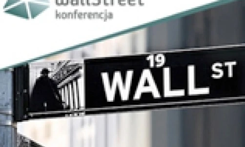 Tabliczka z nazwą ulicy z aluminium na ścianie, z napisem "WALL ST" i "Wall Street" w języku polskim. Tabliczka wskazuje lokalizację konferencji pod numerem 19 na Wall Street.