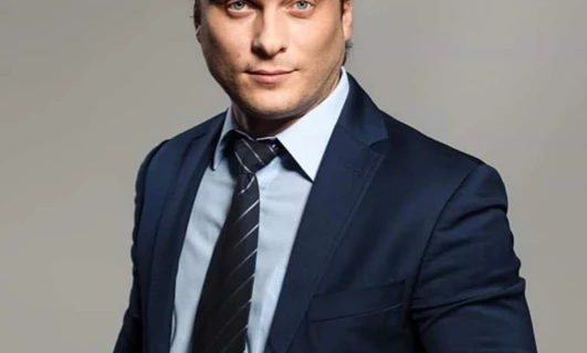 Zblizenie pracownika umyslowego w bialej koszuli, marynarce i krawacie, skupienie na brwiach, czole i kołnierzu.