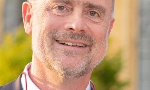 Zblizenie obrazu usmiechnietej twarzy osoby, ukazujacej podbródek, policzek, brwi, czolo i szyje. Osoba wydaje się szczęśliwa, z widocznymi zmarszczkami i gładka skóra.