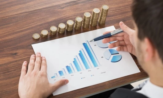 Pracownik umysłowy robi gest palcem i kciukiem, używając artykułów biurowych do rysowania diagramu dla zarządu. Kluczowe słowa: Palec, Gest, Kciuk, Artykuły biurowe, Diagram.