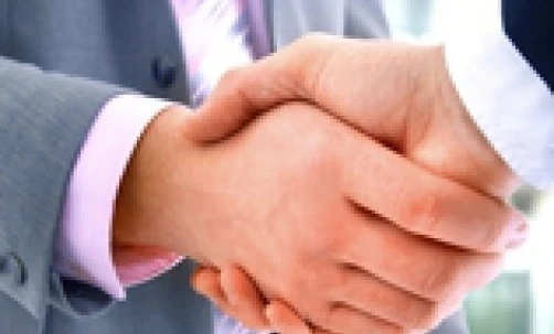 Dwóch pracowników umysłowych witających się uściskając się za ręce w geście współpracy i wzajemnego szacunku. Osoby biznesu nawiązujące kontakty i budujące relacje.