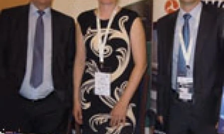 Mężczyzna w eleganckim stroju, w tym garnitur i płaszcz, z uśmiechem na twarzy. Ma na sobie krawat i spodnie, emanując wyglądem pracownika umysłowego. Obraz wyraża profesjonalizm i elegancję.