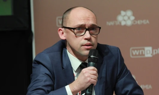 Osoba nosząca okulary i słuchawki, z naciskiem na twarz i brodę. Wyraźnie widoczne logo COCHEMA.