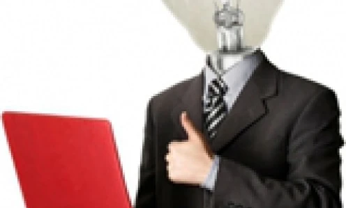 Pracownik umysłowy siedzący przy biurku z urządzeniem elektronicznym i laptopem, otoczony artykułami biurowymi. Słowa kluczowe: Praca, Technologia, Sprzęt komputerowy.