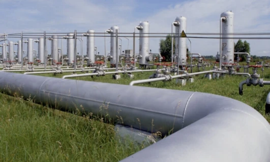 Rozprowadzanie w przemyśle rur stalowych do obudowy w celach transportu rurociągów i inżynieryjnych. Widoczne są również metalowe cylindry i zbiorniki magazynowe.