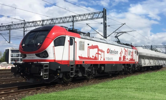 Lokomotywa podróżująca wzdłuż toru kolejowego, część systemu transportu publicznego. Słowa kluczowe obejmują pociąg, transport, tabor, i inżynieria.